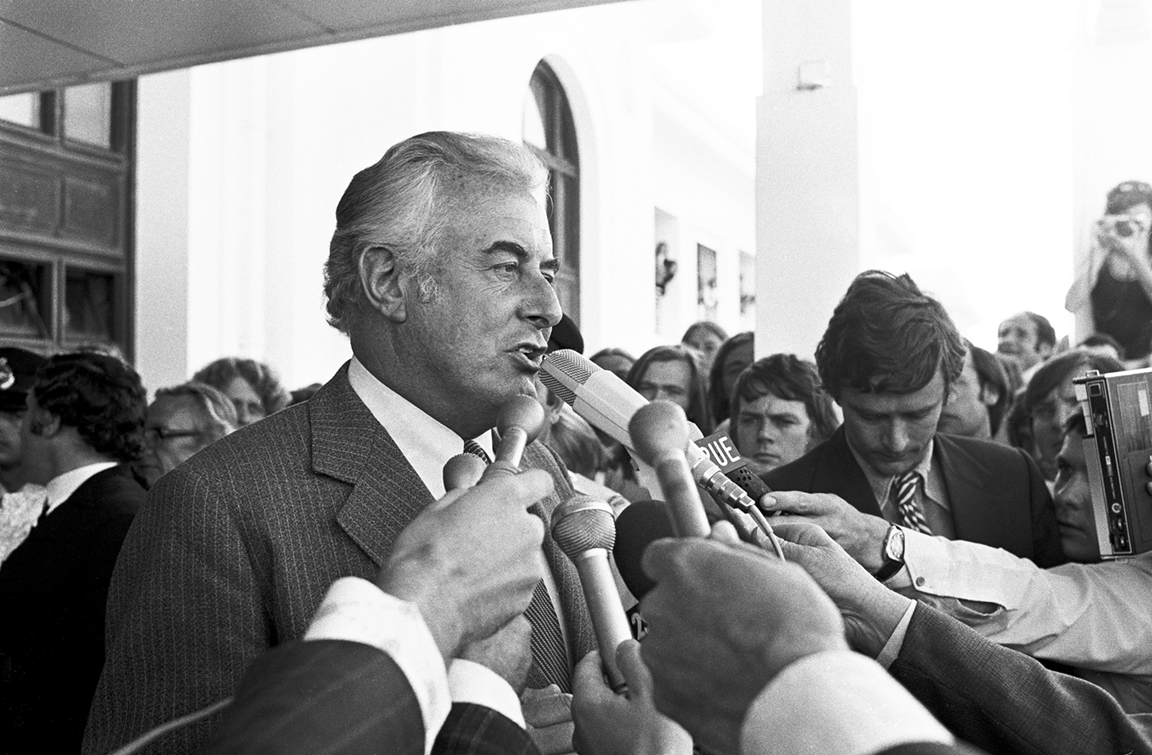 Gough Whitlam talks into multiple microphones on the steps of Old Parliament House.
